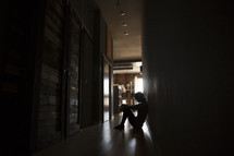 a woman sitting alone in a dark hallway 