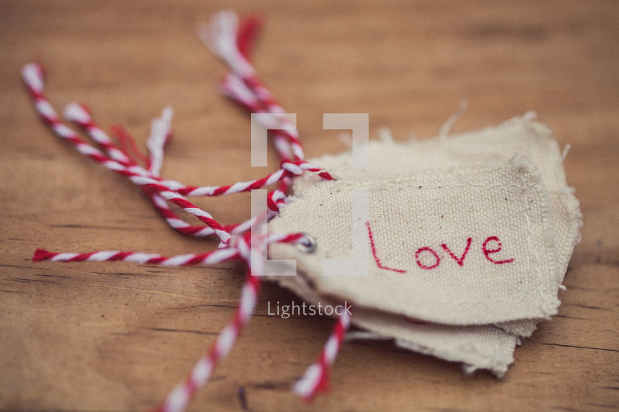 A stack of Christmas gift tags, the top one reading "Love," on a wooden table.