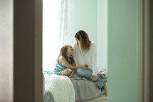 a mother and daughter talking on a bed 