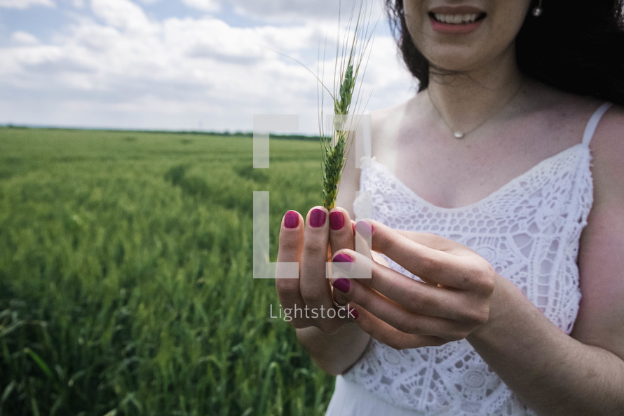a woman holding green wheat 