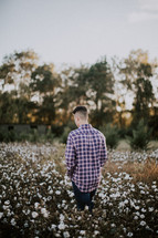 a man walking through a field of cotton 