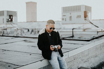 a man with a camera sitting on a roof 