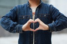 young man creating a heart symbol with his hands 