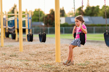 Young elementary school girl alone on a swing, playground, student, school, fatherless, children, child,