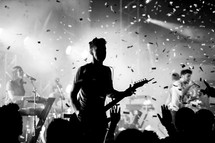 Silhouette of audience and musician on stage with confetti in the air.