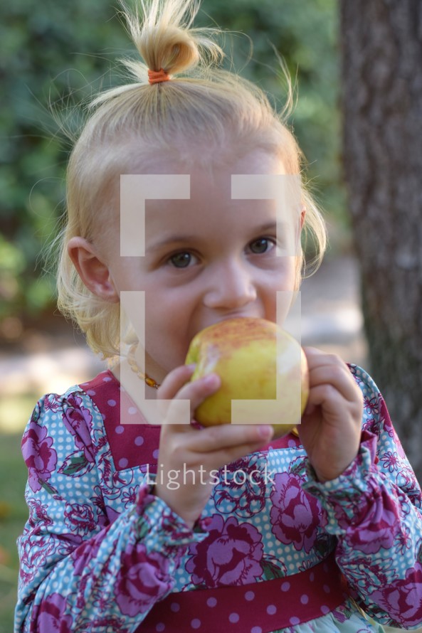 toddler girl eating an apple 