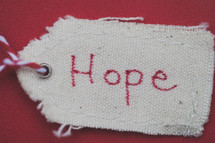 A Christmas gift tag reading "Hope," on a red background.