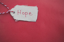 A Christmas gift tag reading "Hope," on a red background.