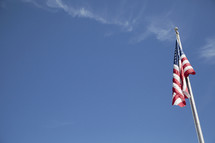 American flag on a flag pole with blue sky.