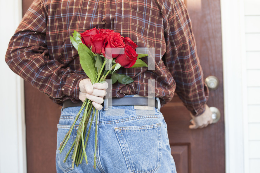 man holding roses behind his back 