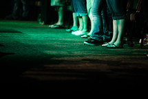 feet of people watching an outdoor concert 