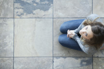 Aerial view of woman praying on her knees on tiles.
