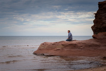 a man kneeling on a beach 