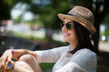 woman in a straw hat and sunglasses sitting outdoors 