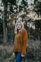 a woman in a sweater standing outdoors in fall 