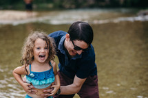 a father and daughter playing in a lake 