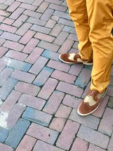 a man in dress shoes standing on brick pavers 