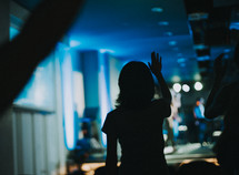 silhouette of a woman with raised hand during a worship service 