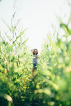 a teen girl standing in a corn field 