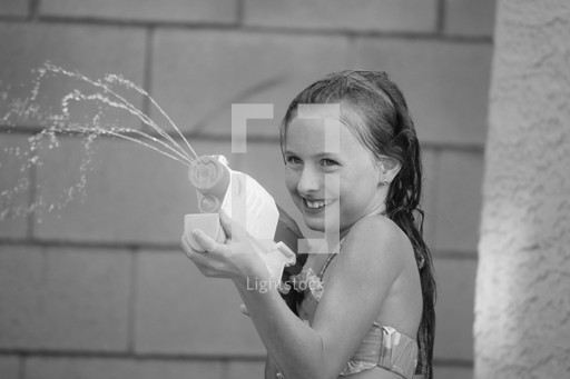 a little girl squirting a water gun.