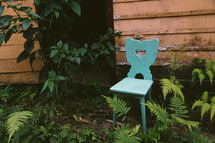 teal chair outdoors in ferns 