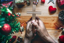 praying hands holding a cross at Christmas 