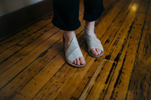 woman's feet in sandals standing on a wood floor 