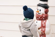 a child looking at a snowman