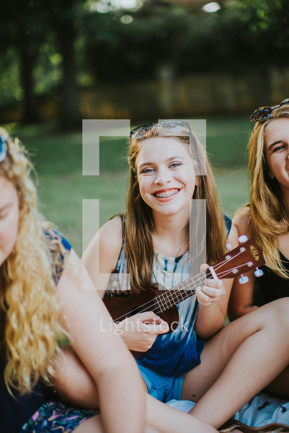 smiling teen girl with braces holding a ukulele 