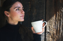 a woman holding a coffee cup looking up 