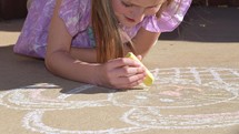 A little girl drawing an Easter bunny with sidewalk chalk 