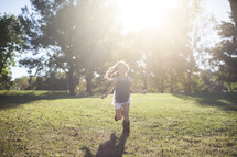 a happy child running outdoors in the grass and sunlight.