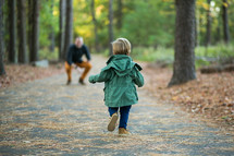 a toddler boy running to his father outdoors 