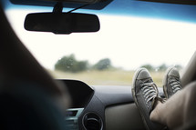 feet on the dashboard of a car.