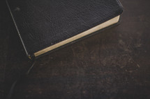 A closed Bible and bookmark on wood