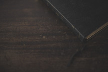 The edge of a bible and bookmark on wood