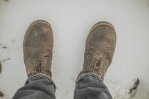 Worn leather boots standing in snow