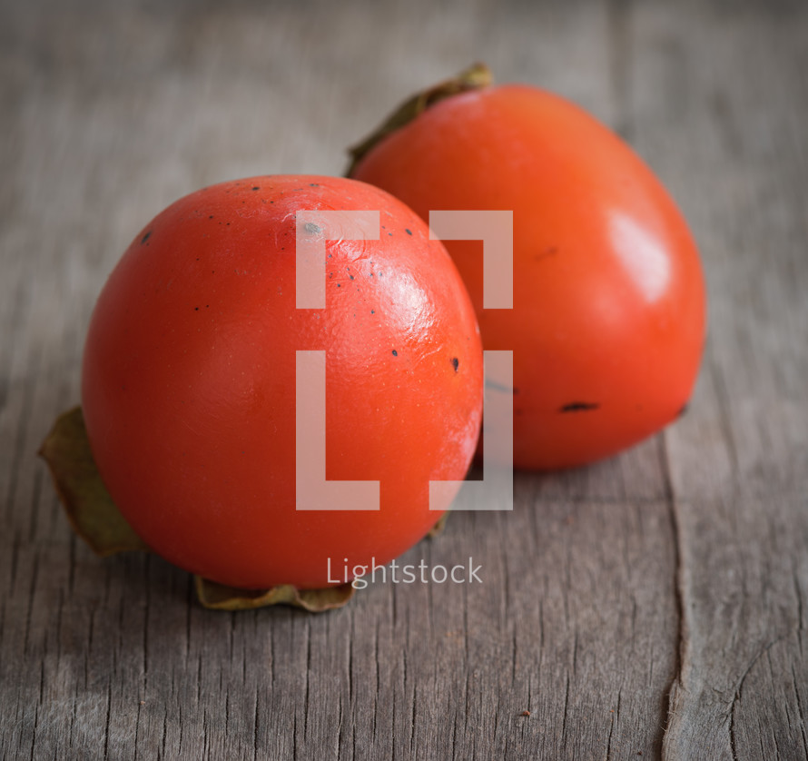 Two red tomatoes on a wooden table.