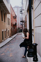 woman texting on a cellphone while leaning against a wall 