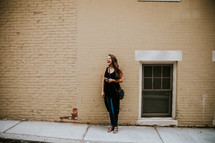 a laughing young woman standing on a city sidewalk 