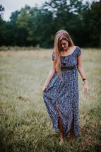 a young woman walking through a field in a sundress