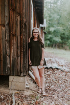 a teen girl standing beside a cabin 