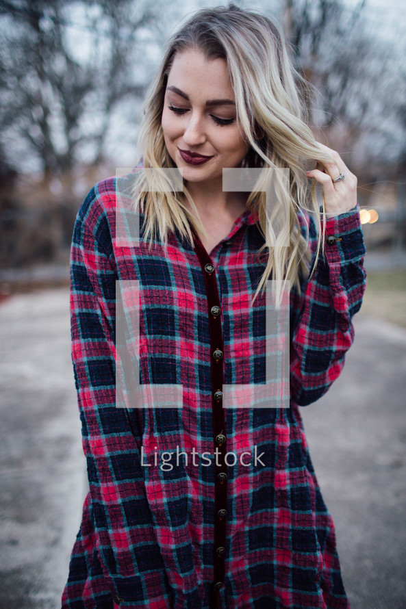 a young woman in a plaid standing outdoors 