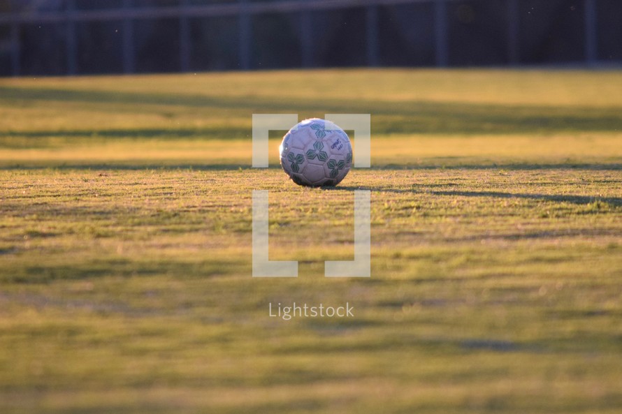 soccer ball on a glowing field at sunset 