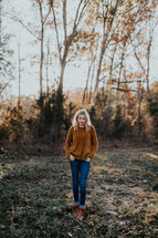 a woman standing in a field in a sweater 