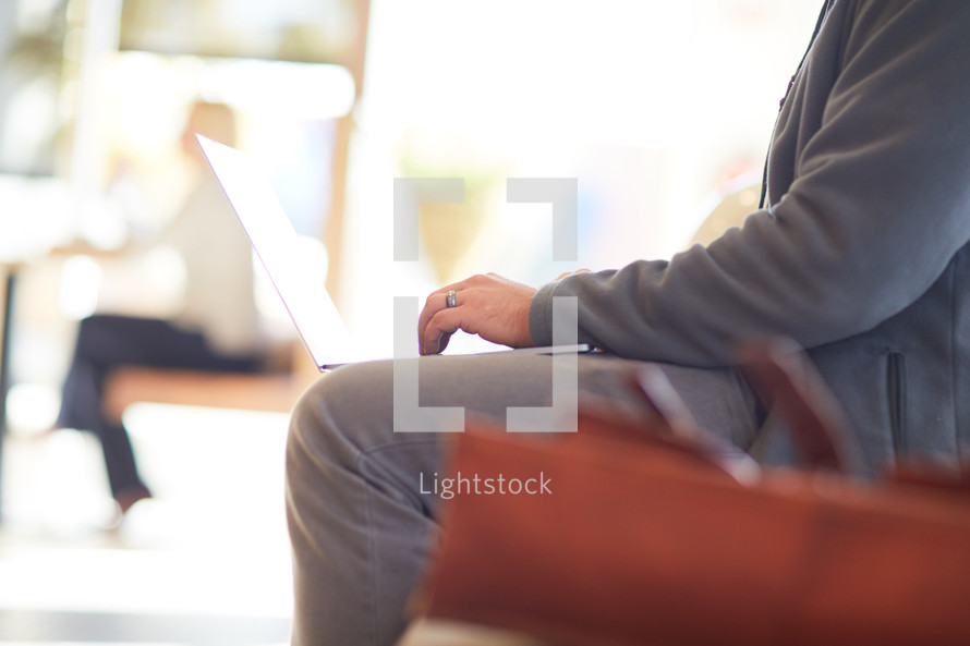 man sitting on a couch with a laptop in his lap 