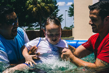 A boy being lifted from baptismal waters.