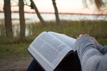 a woman sitting outdoors in fall reading a Bible 