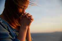 a woman praying by a shore 