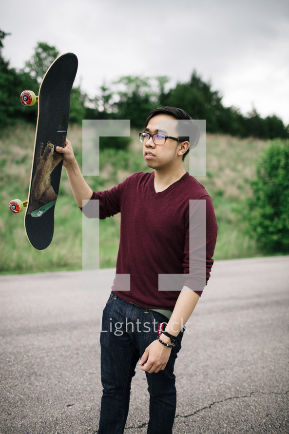 a teen holding a skateboard 